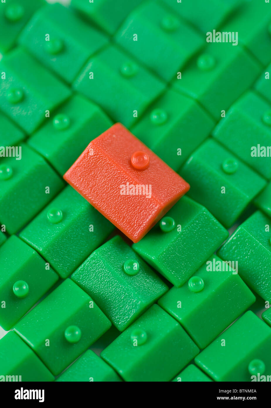 A red Monopoly house amongst a sea of green houses Stock Photo Alamy