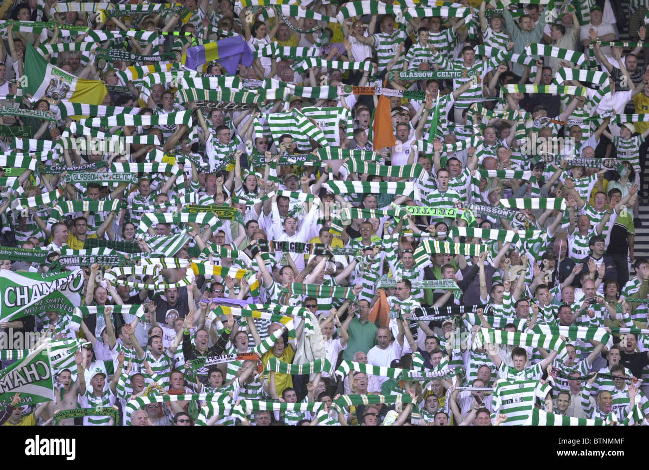 Celtic football fans hold aloft their scarves while singing Stock Photo