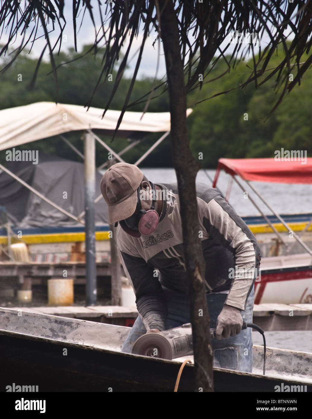 Fisherman using a grinder, carrying out repairs to his boat in Baru, Colombia Stock Photo