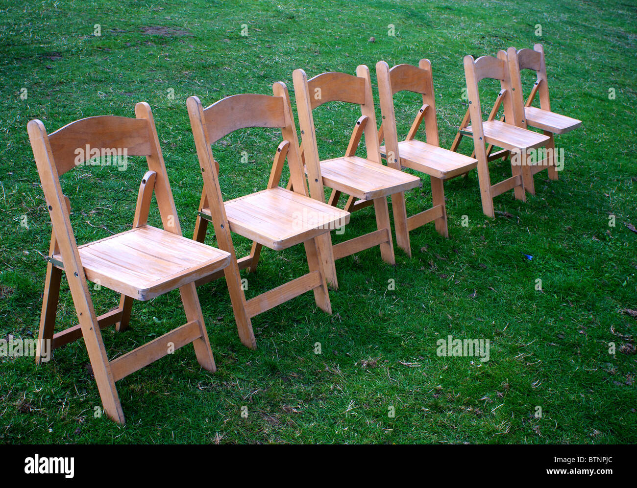 Folding chairs arranged in a straight line outdoors Stock Photo