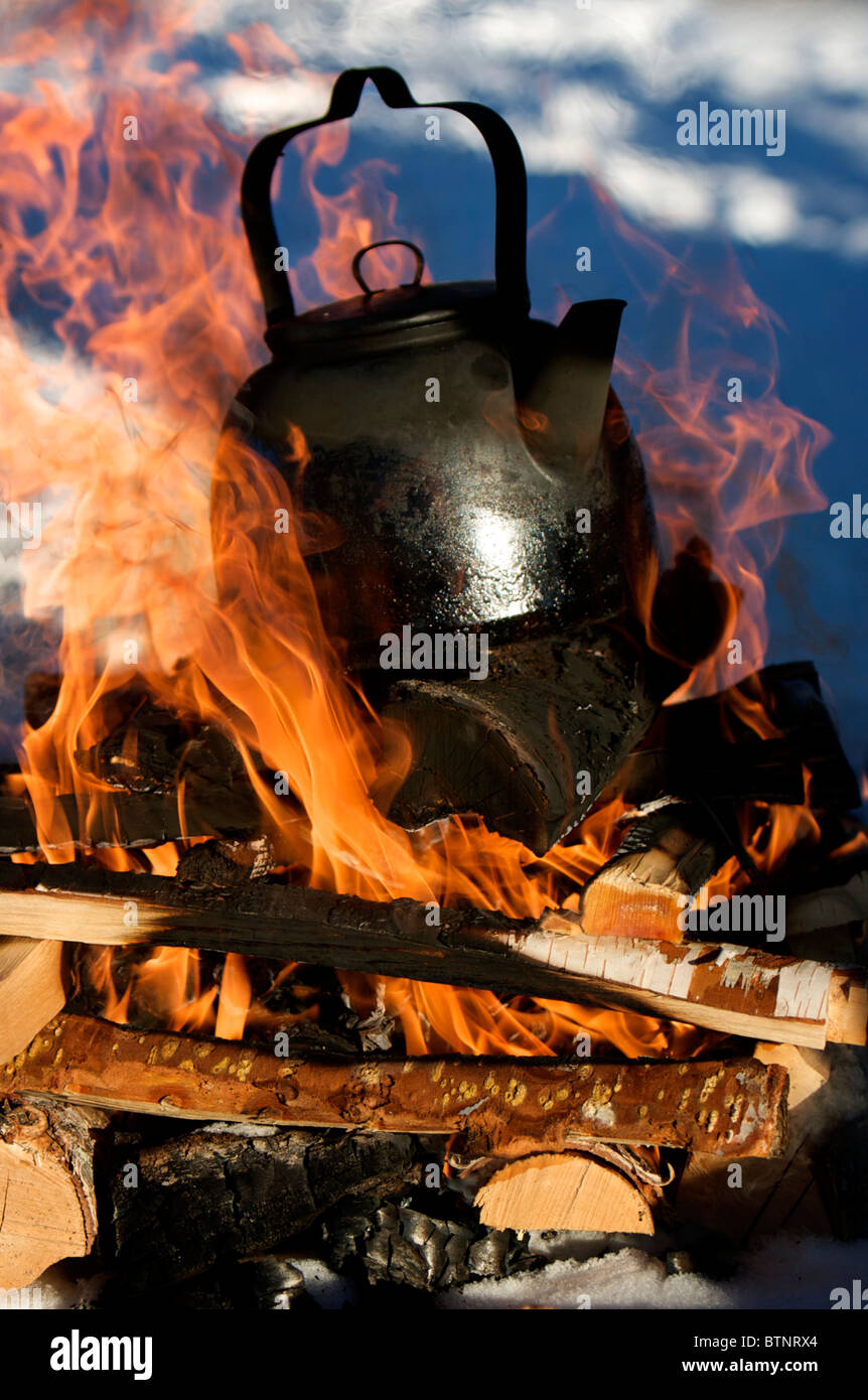 Boiling water in a kettle over an open fire in the winter snow, for a