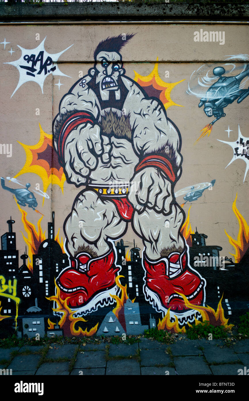 Graffiti showing a muscular giant monster being attacked by helicopters, Munich, Germany Stock Photo