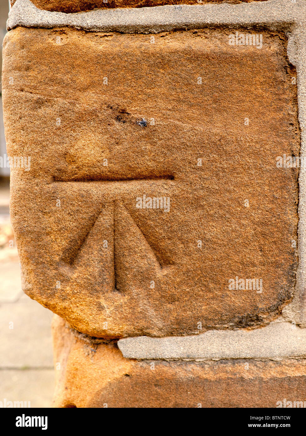 Surveyors benchmark at a measured height above sea level cut in a sandstone wall Stock Photo