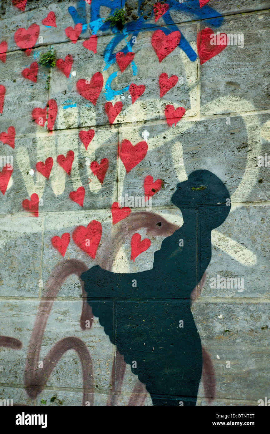 Graffiti showing a young girl in black letting red hearts escape / fly from her apron, Wall in Munich, Germany Stock Photo