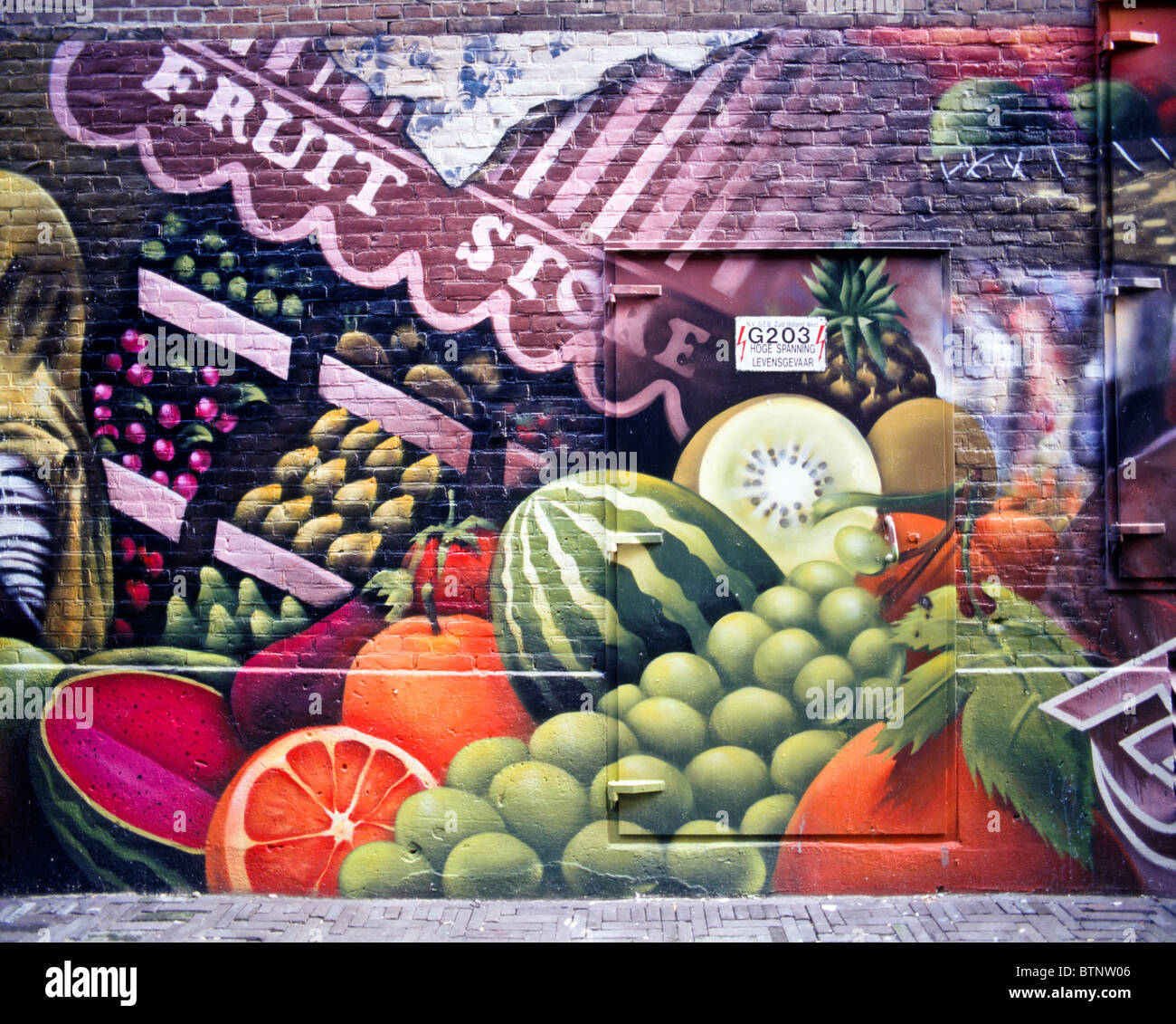 Graffiti on a brick wall of fruits & vegetables and a dark skinned woman with a scarf in a narrow alley, The Hague, Netherlands Stock Photo