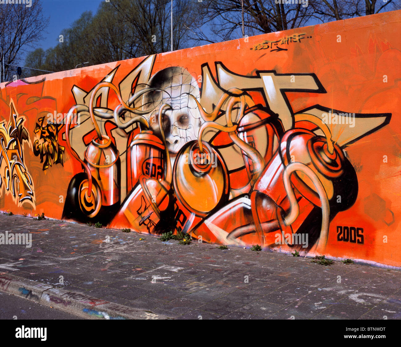 Graffiti showing spray cans in the foreground and a pale white face covered with a net in the background, Delft, NL Stock Photo