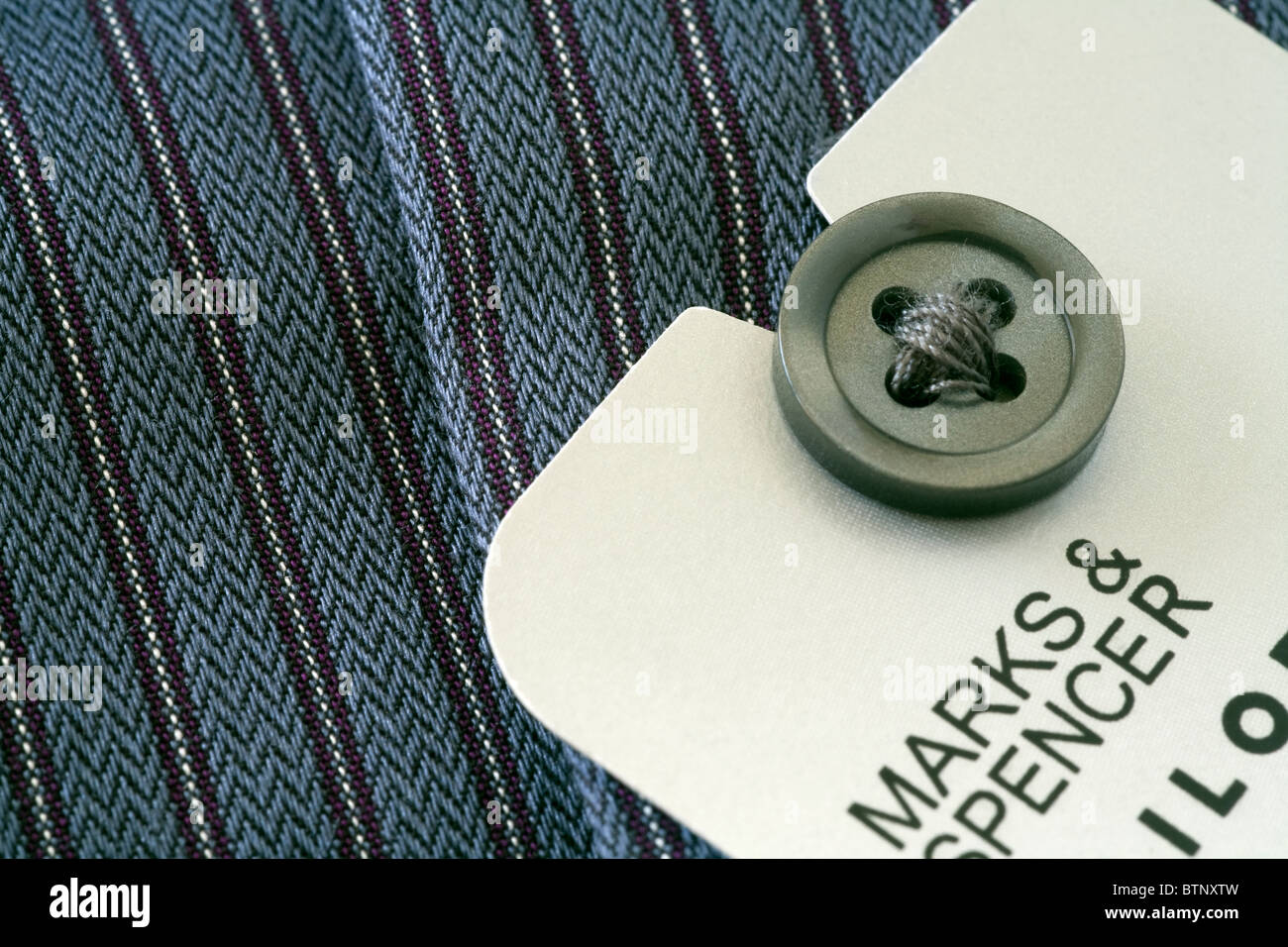 A new Marks and Spencer mens shirt with detail of the button hole and with the promotional  information label revealed. Stock Photo