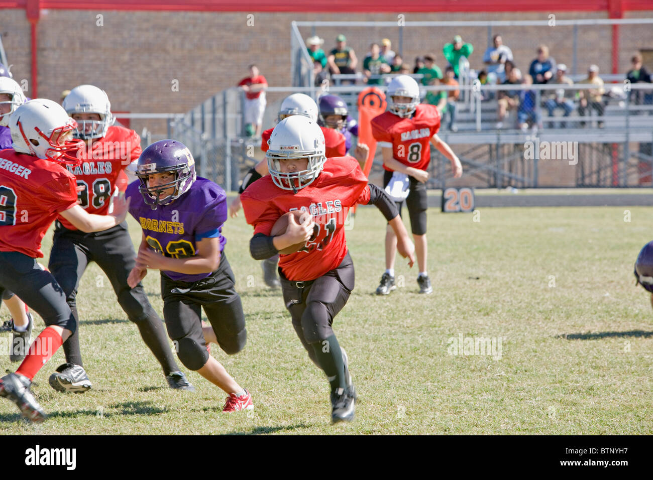 Youth American football with players running play and one carrying ball Stock Photo