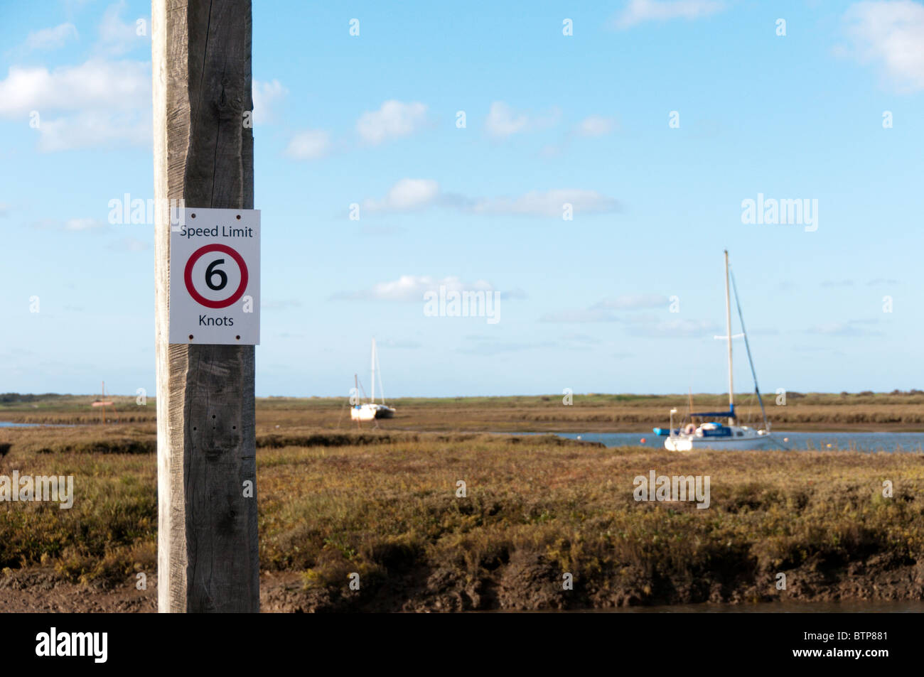 A speed limit sign of 6 knots on a mooring post at Brancaster Staithe, Norfolk, England Stock Photo