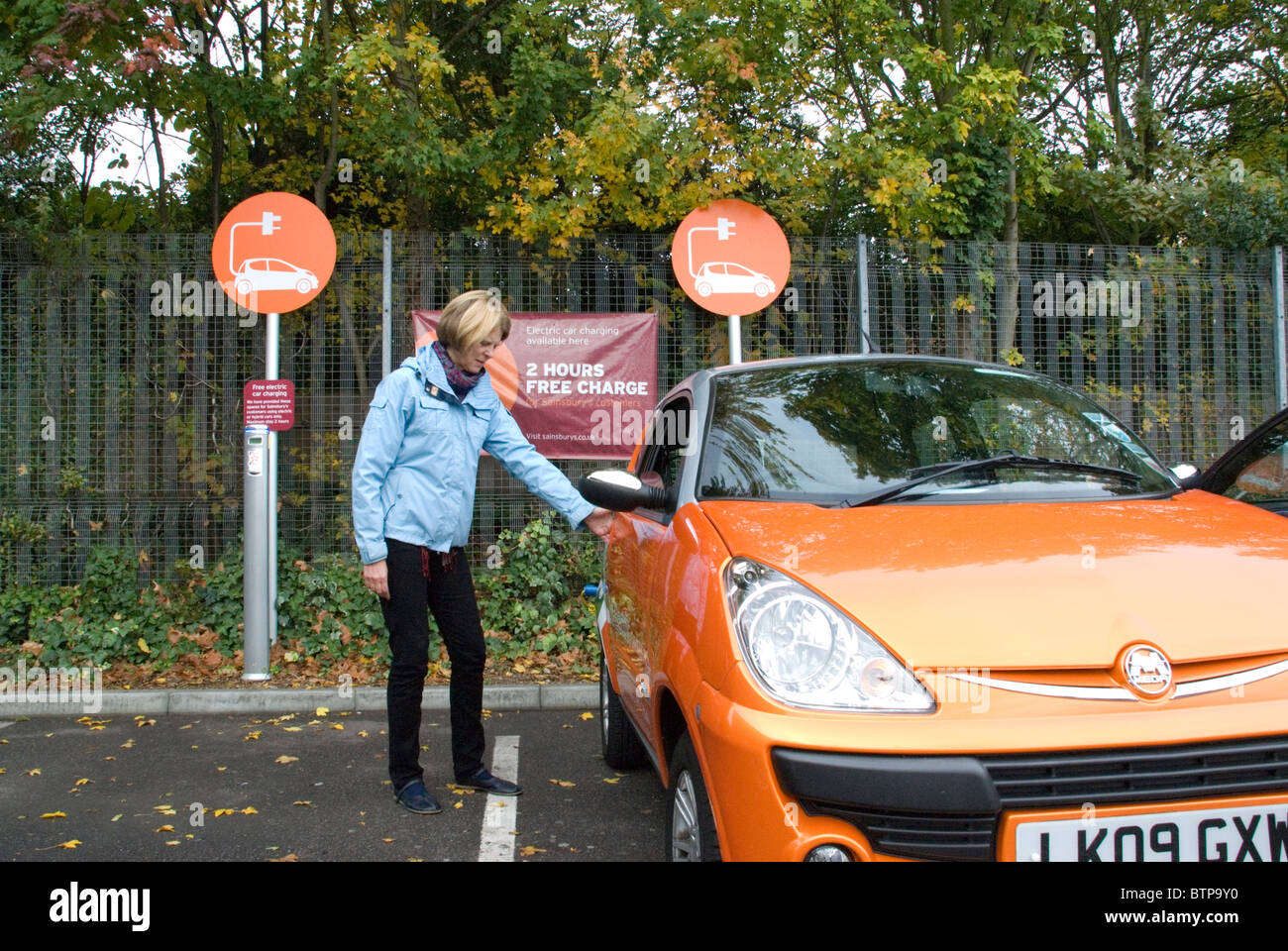 Woman getting in to electric car rented from GoGo Electric Cars free EV Elektrobay charging point Sainsbury’s London Stock Photo