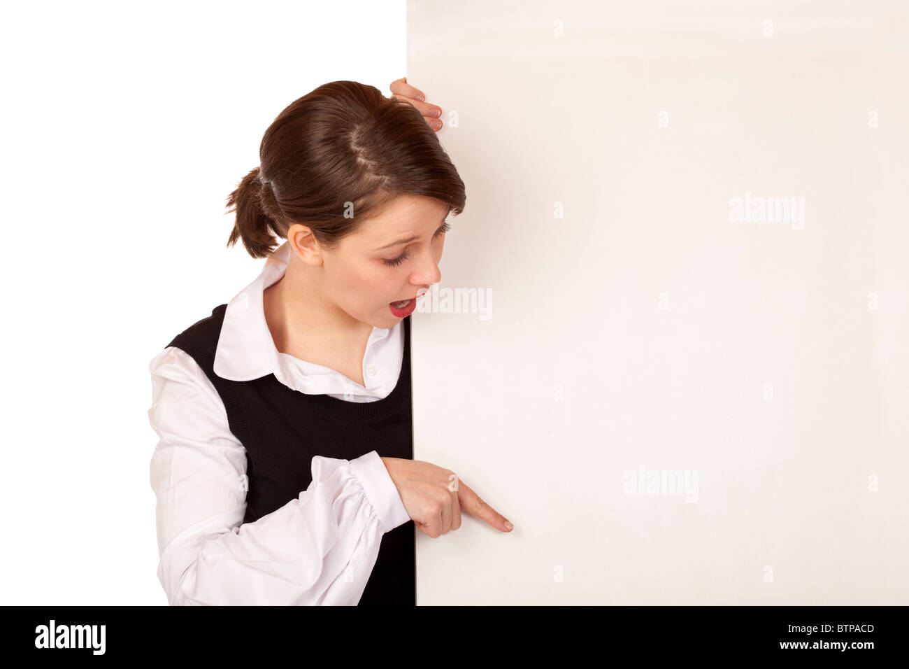 Young surprised woman points with finger on blank board. Isolated on white background. Stock Photo