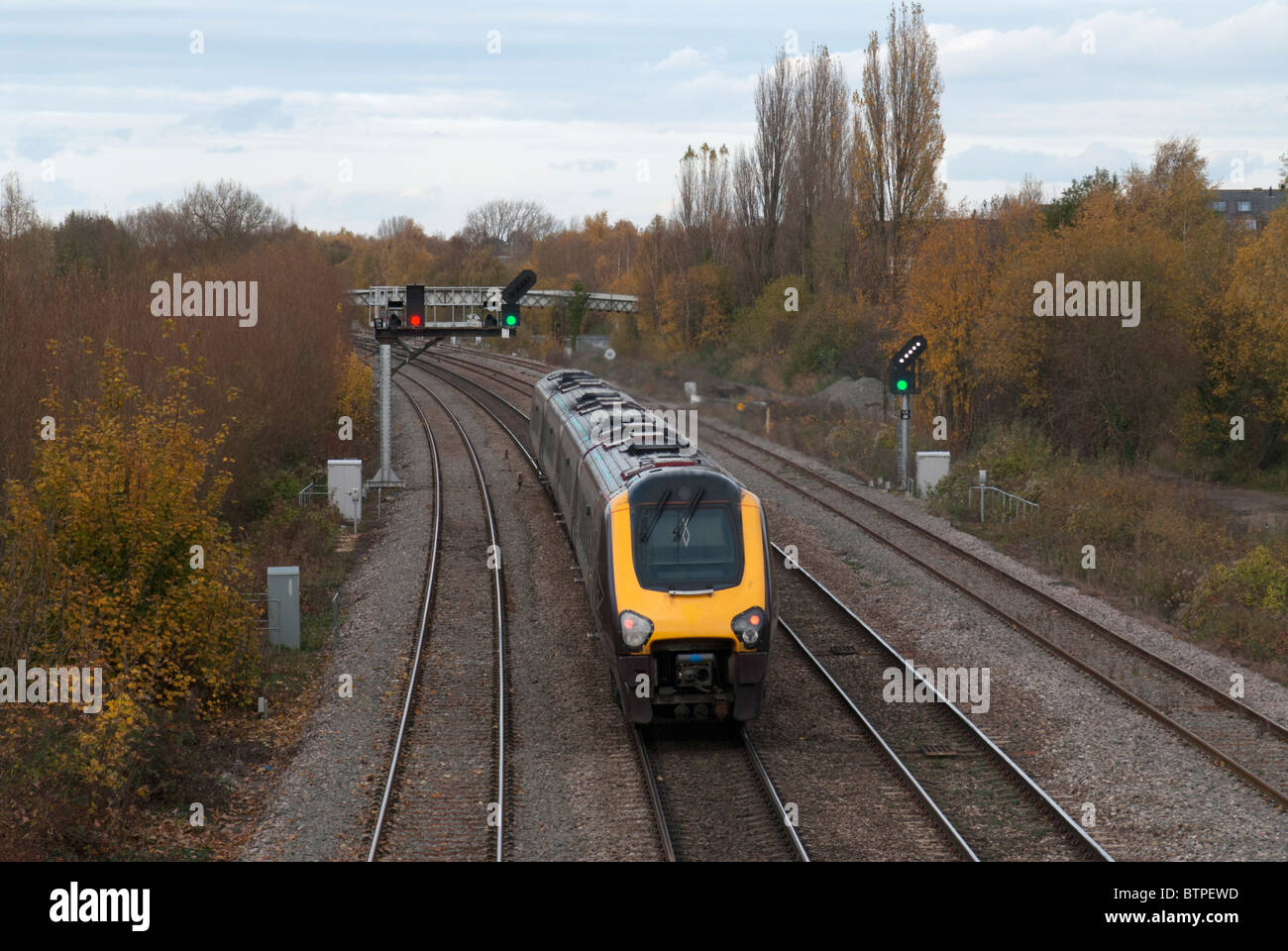 UK Train on Tracks Traveling Through Green Signal Stock Photo
