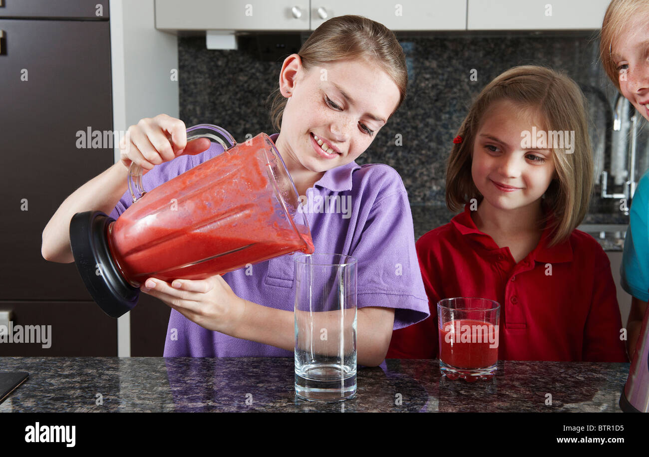 Girls pouring fruit juice from blender Stock Photo