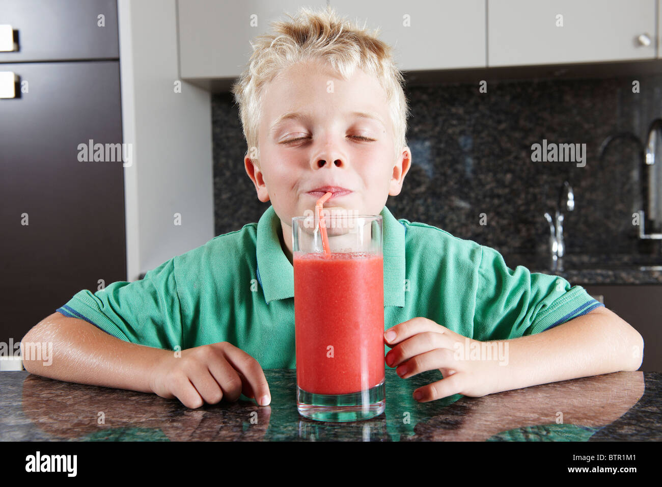 Boy drinking fruit juice with straw Stock Photo