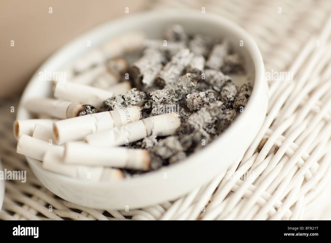 Selective focus photo of white cigarette butts in white ash tray. Stock Photo