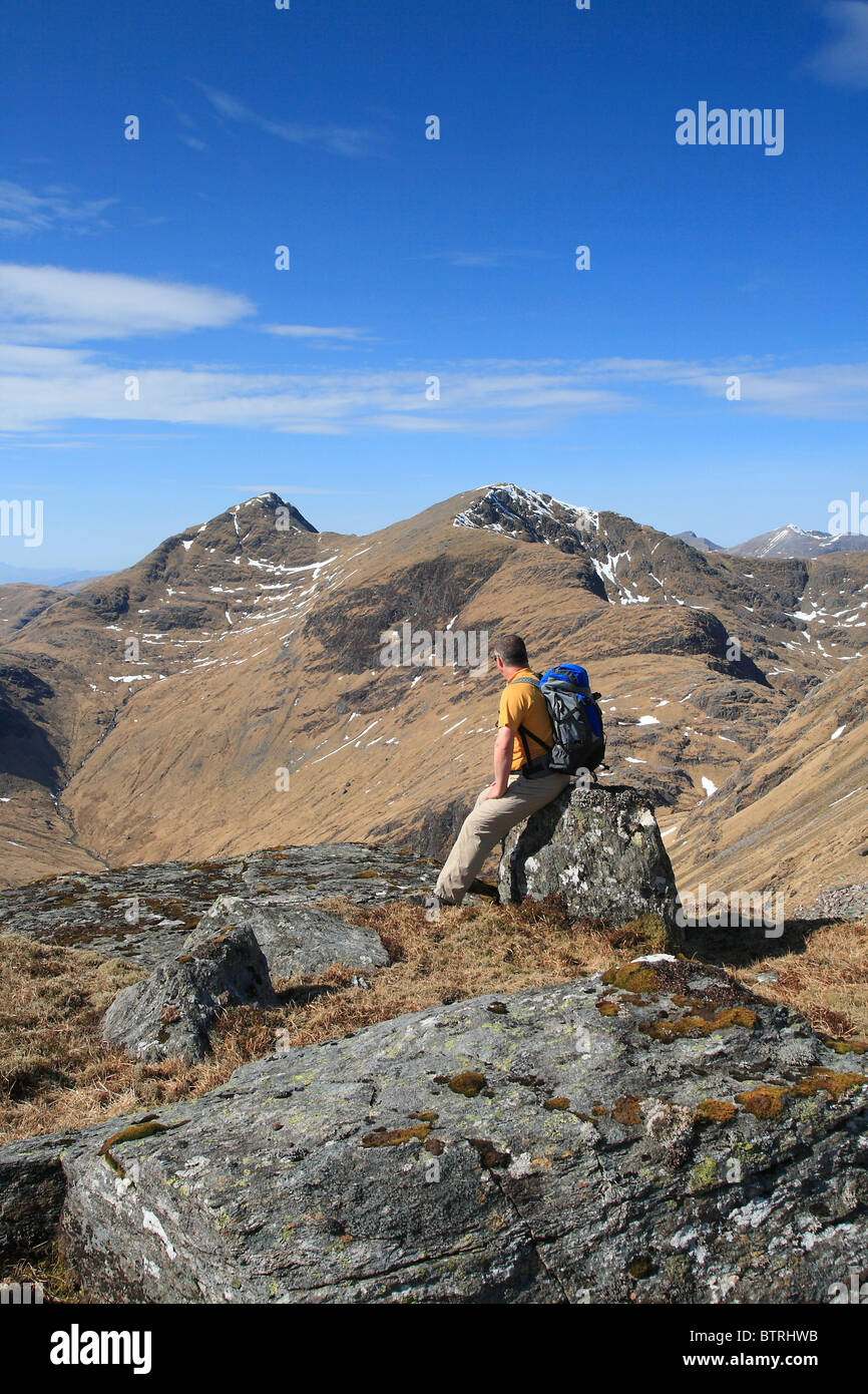 Hillwalker resting on Beinn Maol Chaluim while looking across to Sgor na h-Ulaidh. Stock Photo