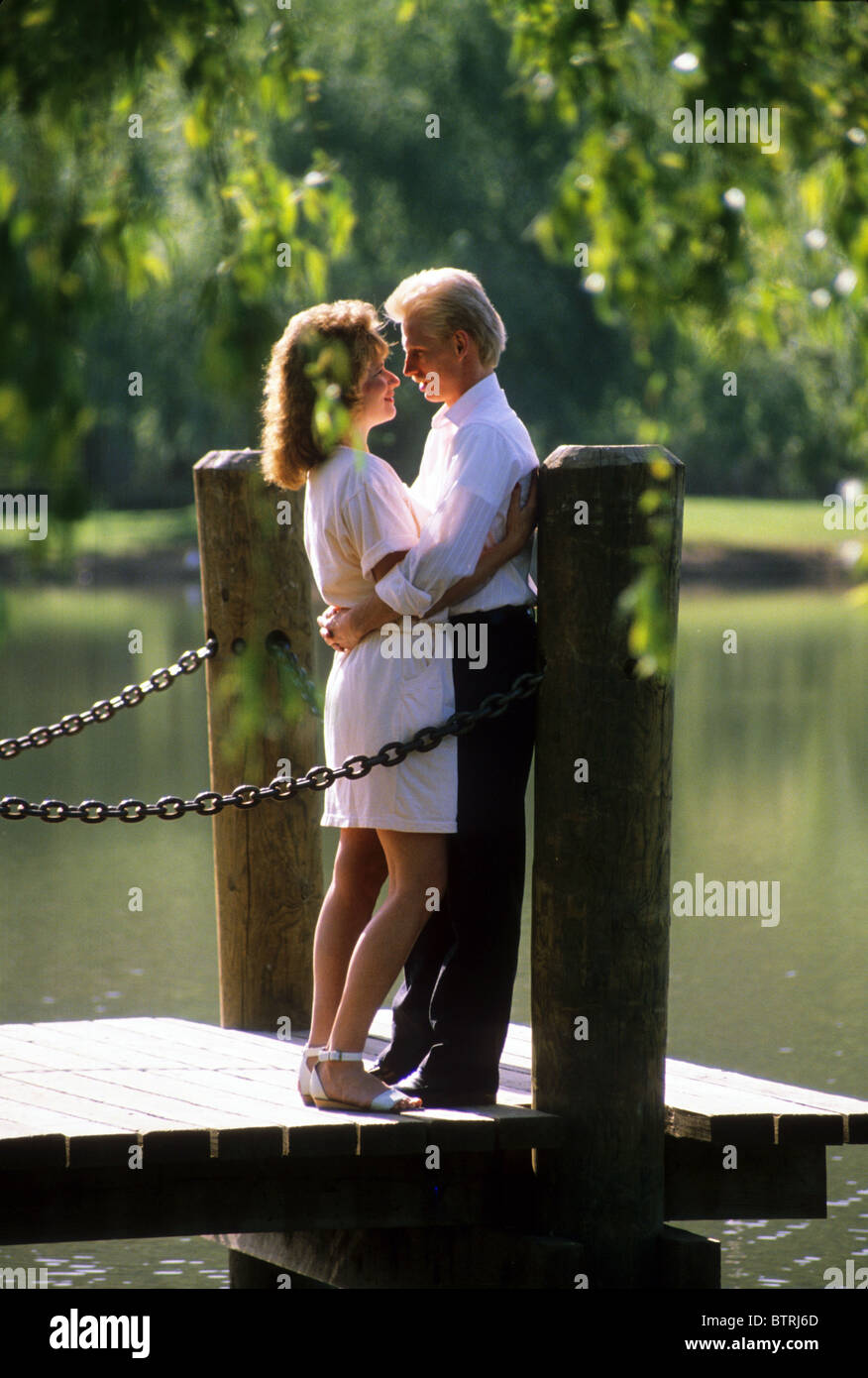 young couple hug snuggle kiss pier lake park sun touch love hug share enjoy  company date man woman sex Stock Photo - Alamy