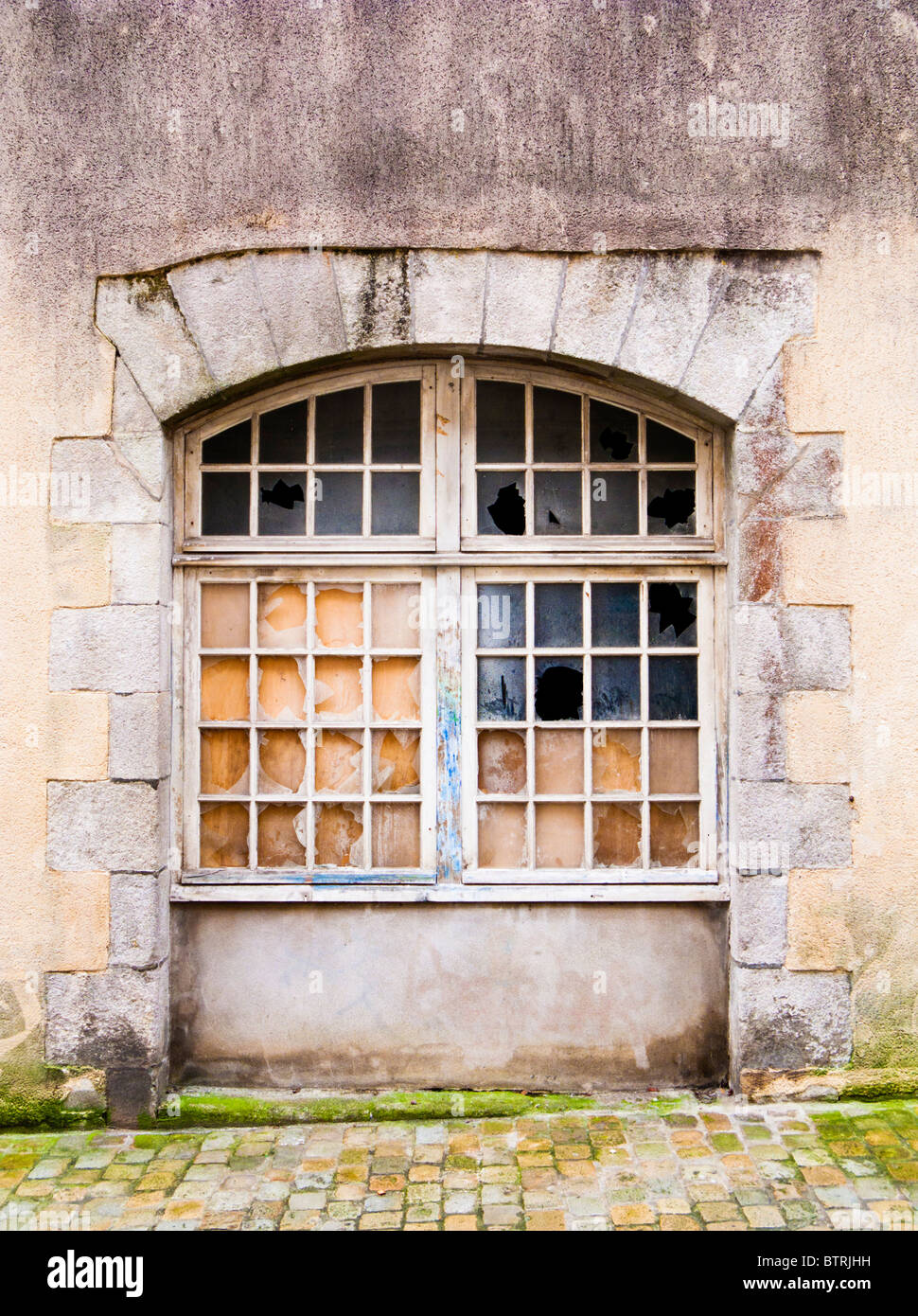 Arched window with broken panes of glass Stock Photo