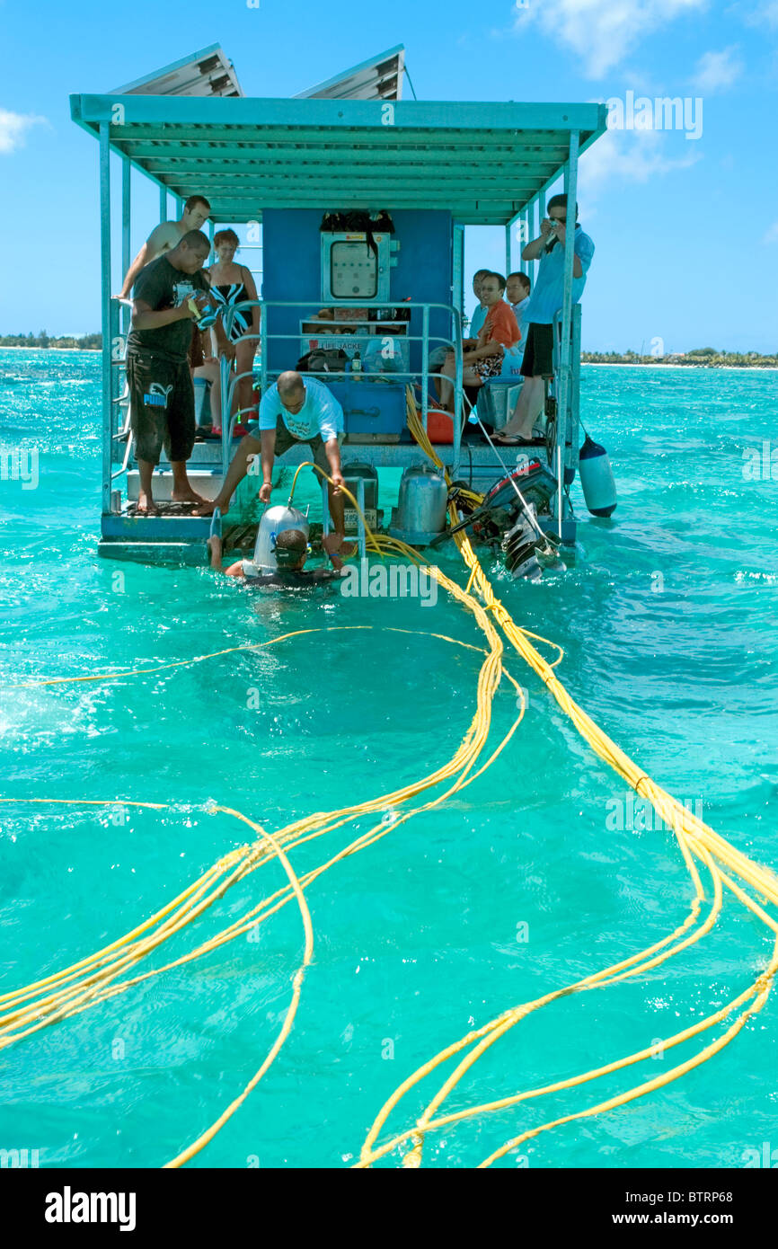 Tourists in Mauritius descending from the platform for the famous undersea walk anchored over the reef close to Grande Baie Stock Photo