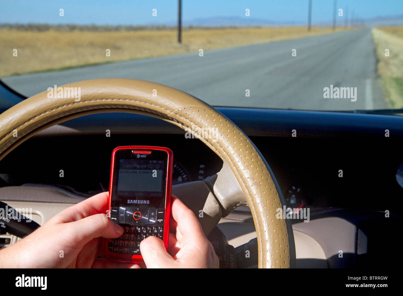 Text messaging on a cell phone while driving in Idaho, USA. MR Stock Photo