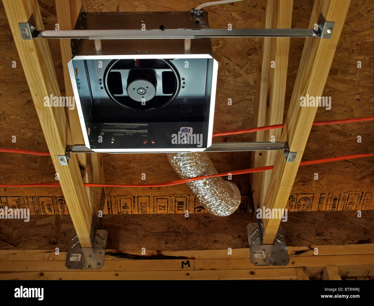 construction detail ceiling fan box pipe tube in roof black metal fixture with red wires rafters vent Stock Photo