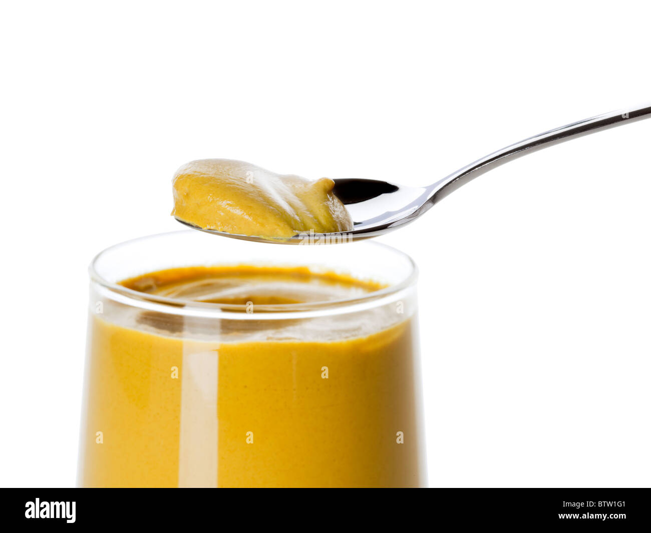 taking a spoonful of mustard from the glass Stock Photo