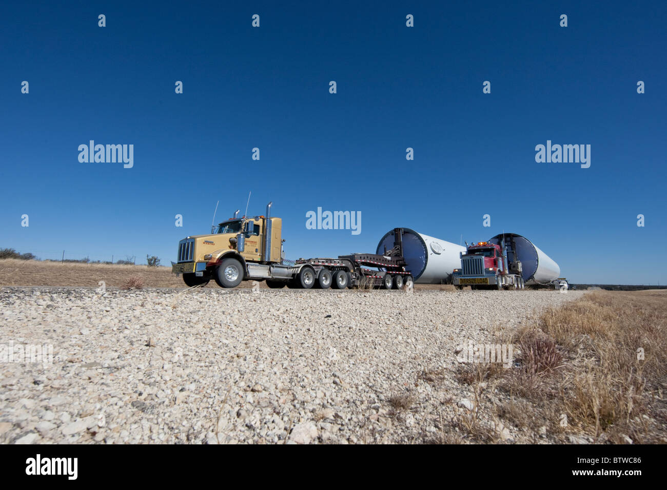Tractor-trailer trucks in a rural area near San Angelo TX haul components of a high-tech windmills to a wind farm in West Texas. Stock Photo
