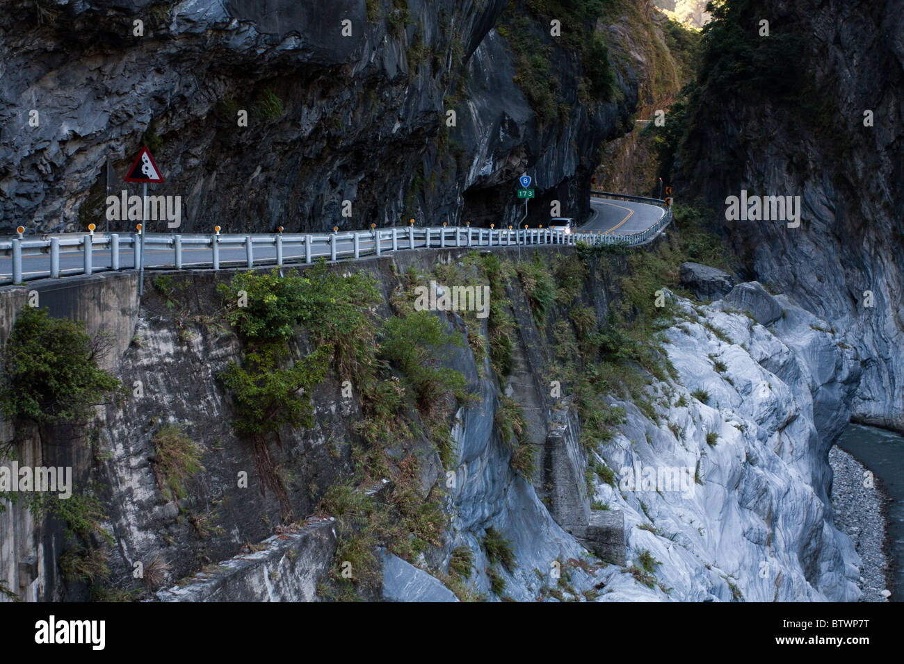 Cliffside road under rock overhang and stream flowing through marble canyons, East-West Central Cross-Island Highway, Taroko National Park, Taiwan Stock Photo