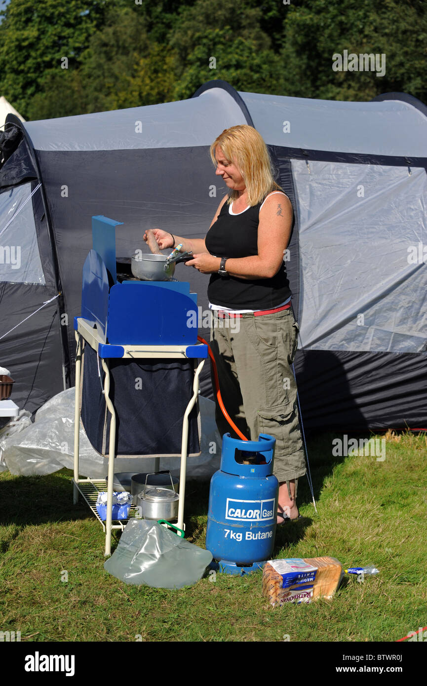 A woman makes breakfast next to her tent whilst camping in the Sussex Stock Photo