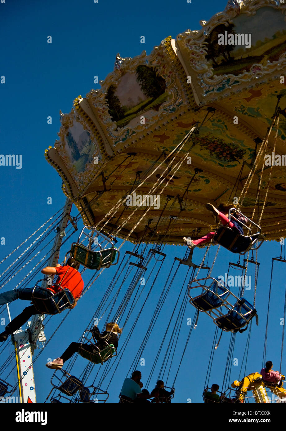 Traditional chair swing carousel in action against clear blue sky Stock Photo