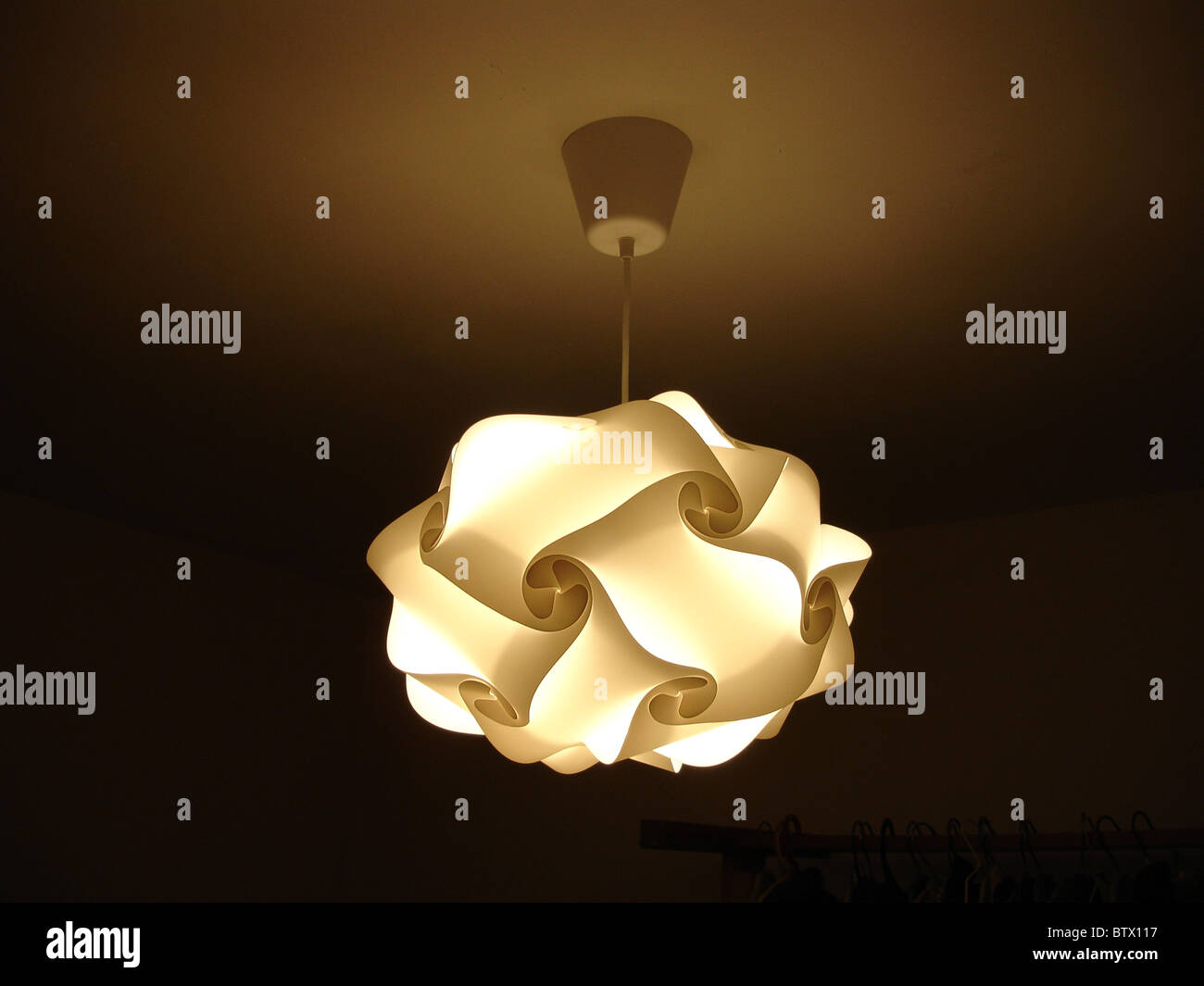 Designer lampshade suspended from ceiling with light on Stock Photo Alamy