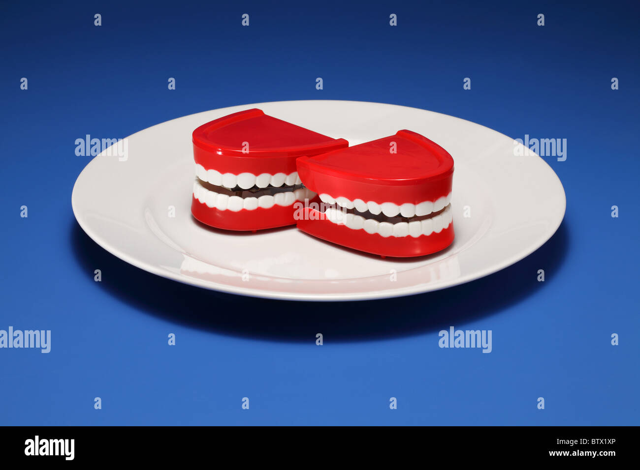 Two plastic gums and teeth on a white dinner plate Stock Photo