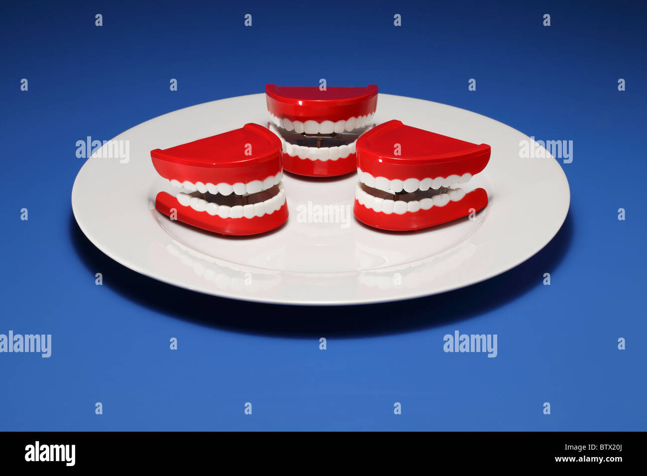 Three plastic gums and teeth on a white dinner plate Stock Photo