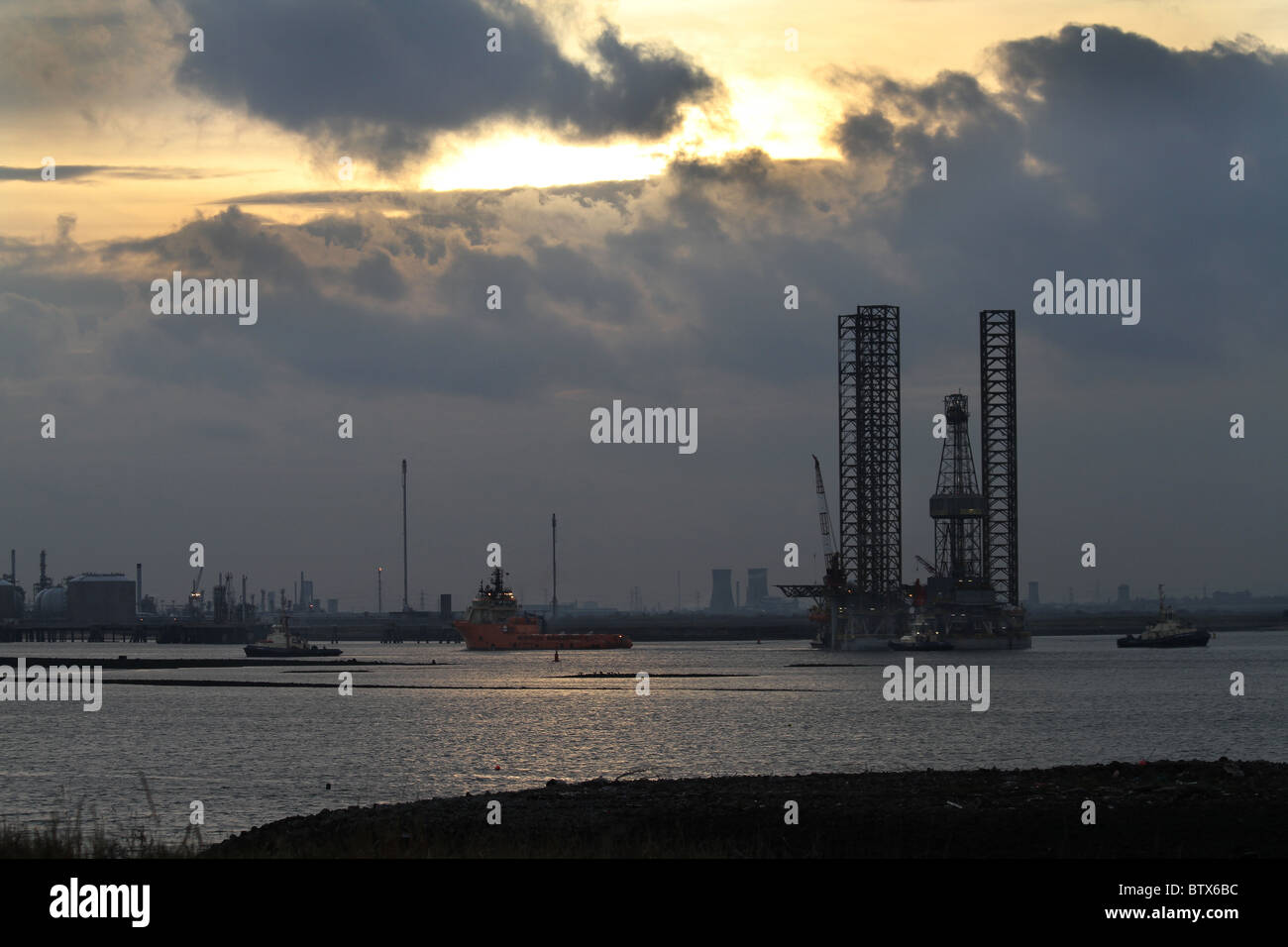 Old north sea drilling platform being towed into Teesport by ocean going and small tugs to be scrapped. Stock Photo