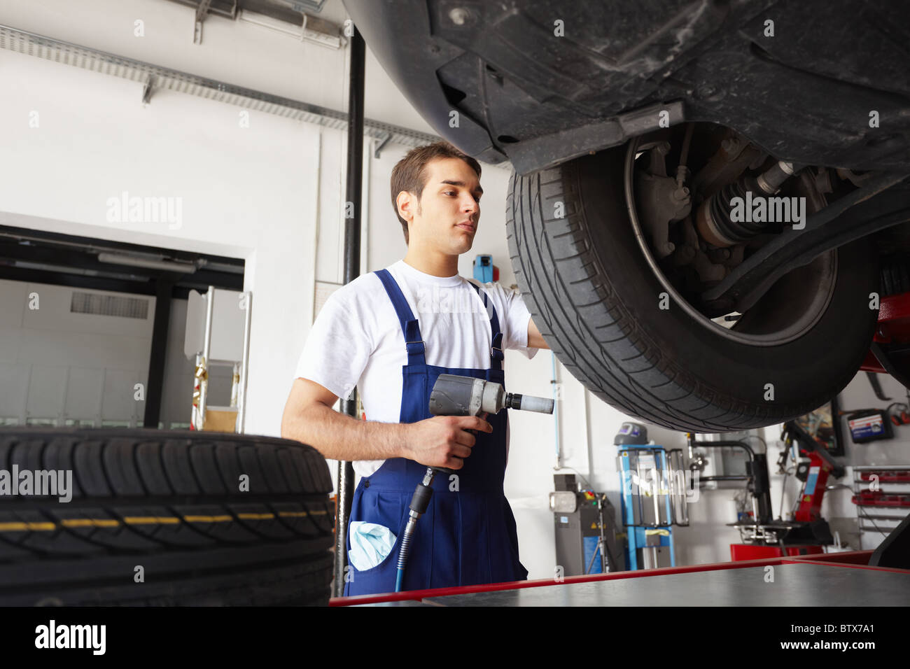 mechanic replacing car tyre in auto repair shop. Low angle view Stock Photo Alamy