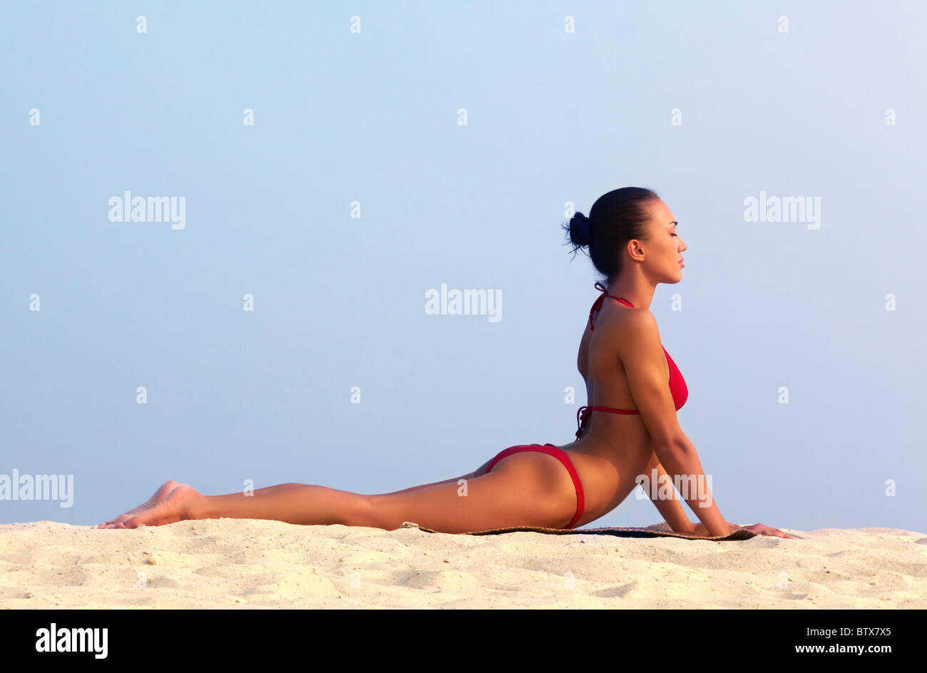 Image of female in red bikini sunbathing on sandy beach during vacation Stock Photo