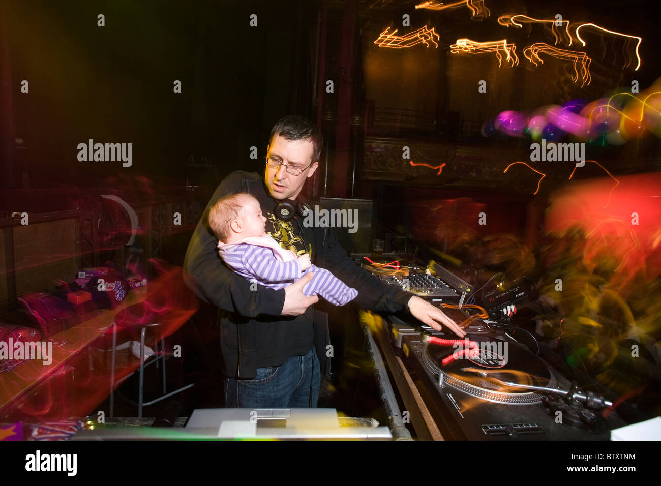 DJ with 6 month old daughter play some tunes on the mixing desk at Baby