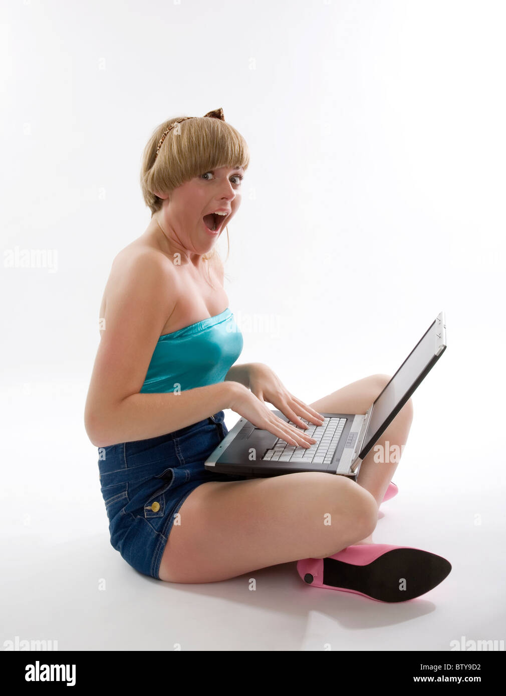 Shocked girl sitting on floor with laptop Stock Photo