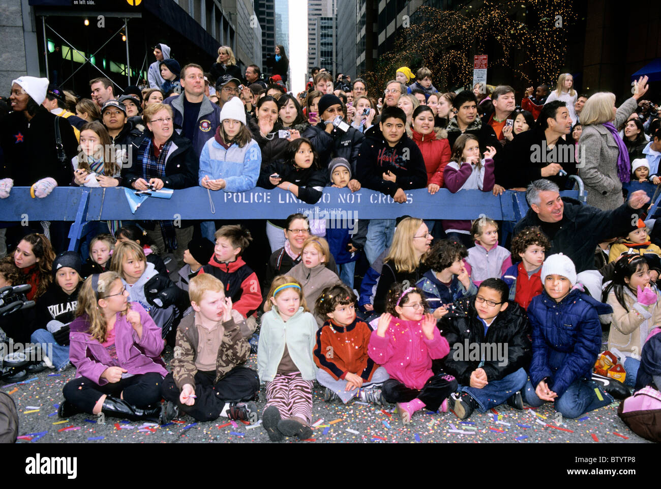 New York City People Sitting And Standing On The Street Watching Macy's  Thanksgiving Day Parade Behind A Police Barrier Stock Photo - Alamy