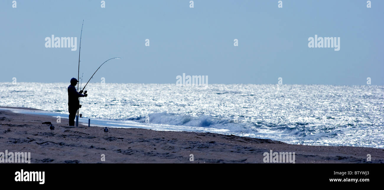 man is alone on the beach at Assateague Island National Seashore fishing in the Atlantic Surf Stock Photo