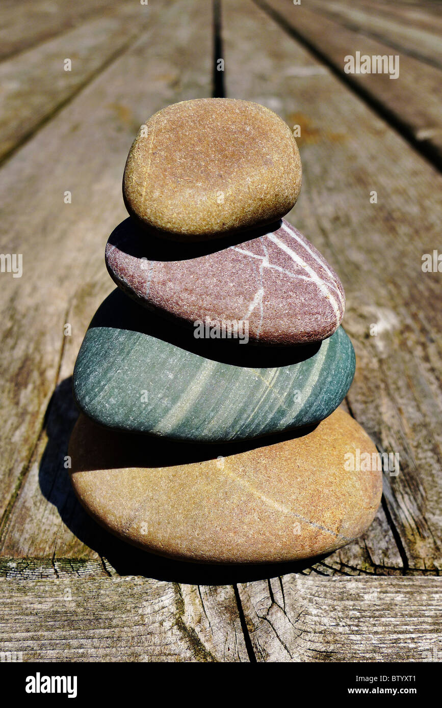 Stacked smooth stones on a wooden deck. Stock Photo