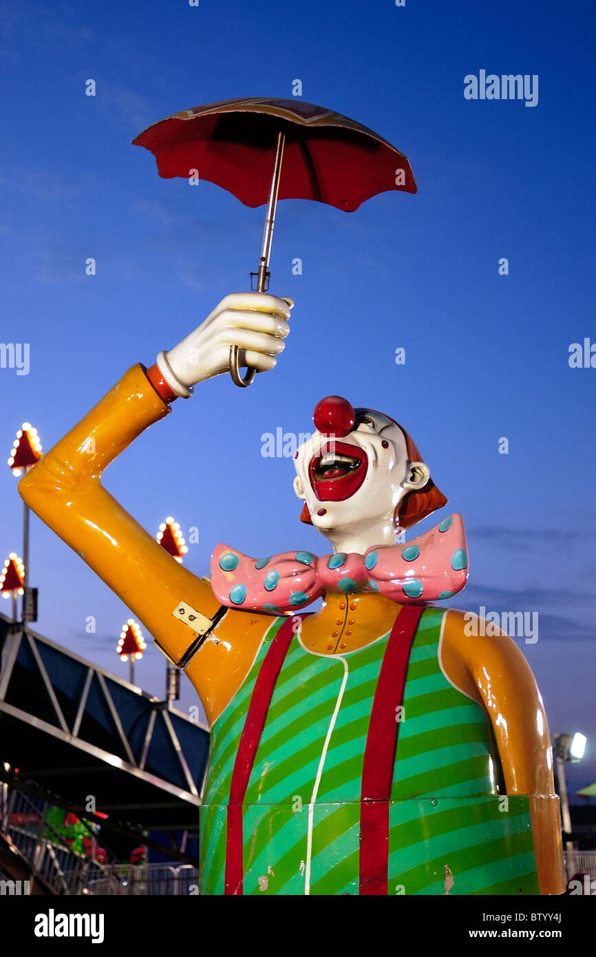 Colorful amusement ride for children at a local fair at night. Clown holding an umbrella. Stock Photo