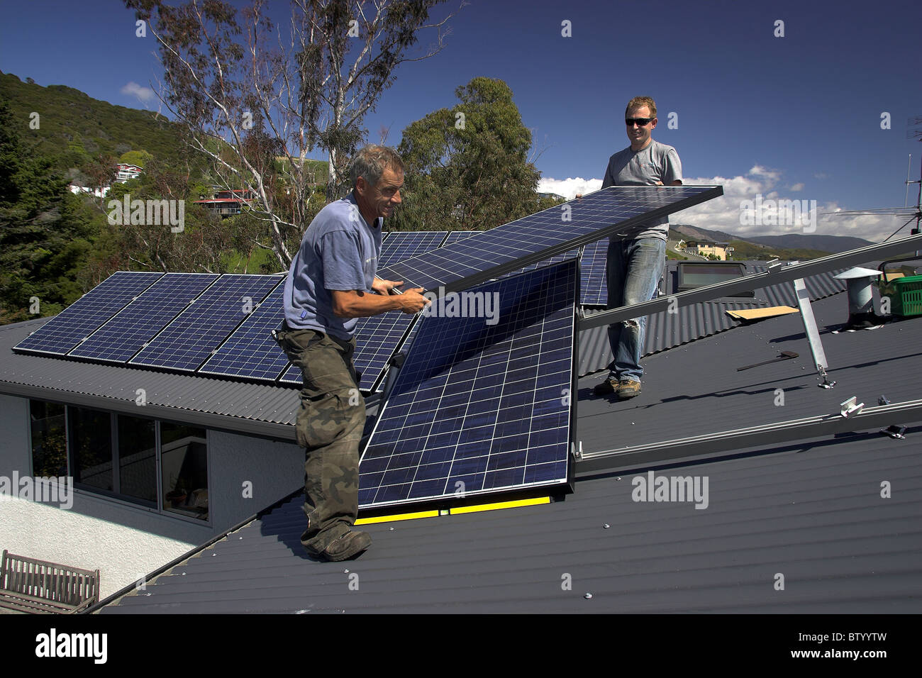 Photovoltaic solar panels being fitted by tradesmen to a house in