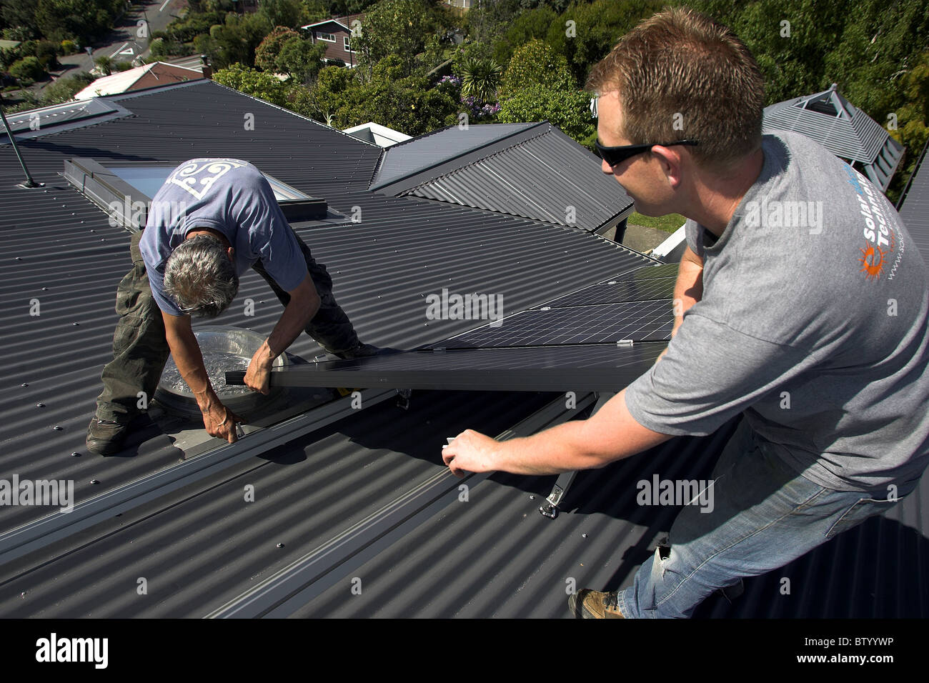 Photovoltaic solar panels being fitted by tradesmen to a house in