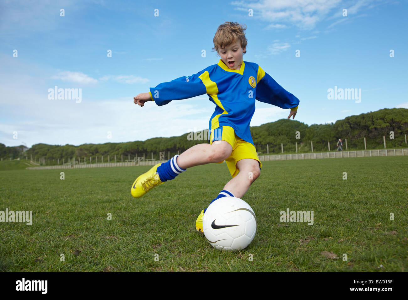 Young boy kicking football Stock Photo