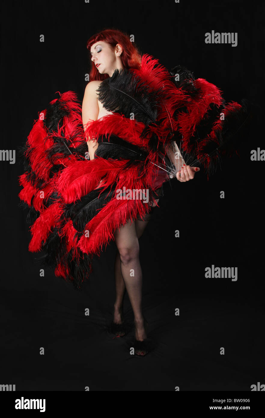 Burlesque Performer Dancing with Red and Black Fans Stock Photo