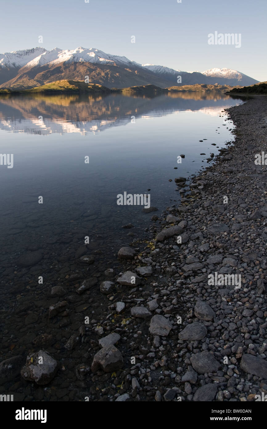Mountain reflection at a stone lakeshore in Wanaka , new zealand Stock Photo