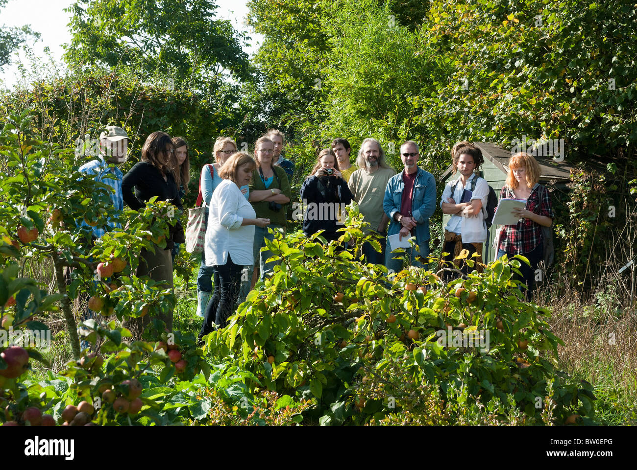 Group of permaculture design students being shown her garden by Maddie Harland Stock Photo
