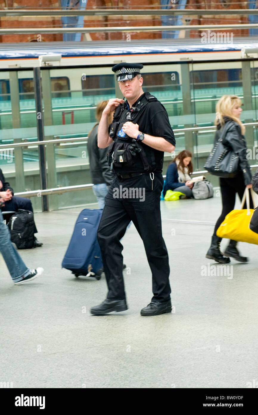 St Pancras Station , policeman or cop patrols walking past travellers by Eurostar platform on upper causeway Stock Photo