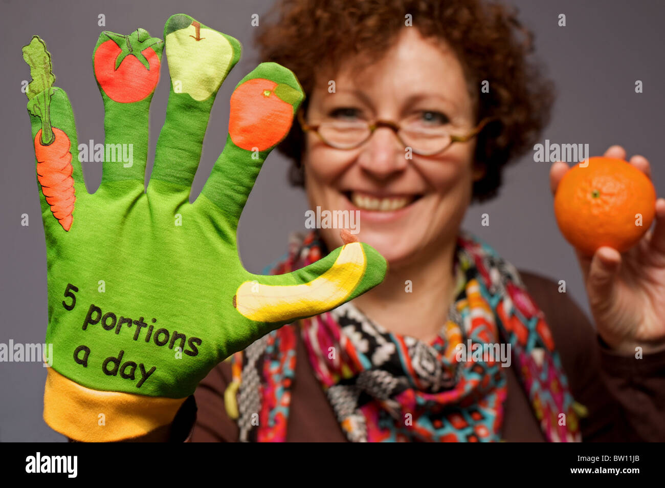 Classroom assistant teaching the five portions of fruit and vegetables a-day Stock Photo